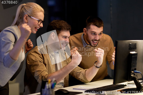 Image of business team celebrating success at night office