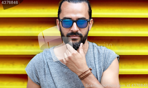 Image of close up of man in sunglasses touching beard