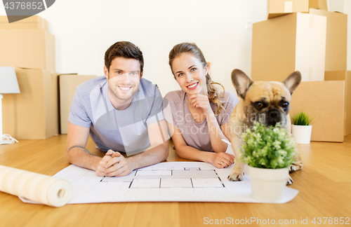 Image of couple with boxes, blueprint and dog at new home