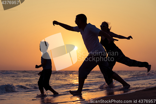 Image of Father mother and  son  playing on the beach at the sunset time.