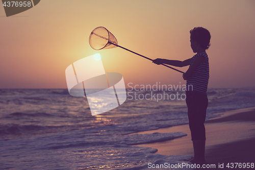 Image of One happy little boy playing on the beach at the sunset time.