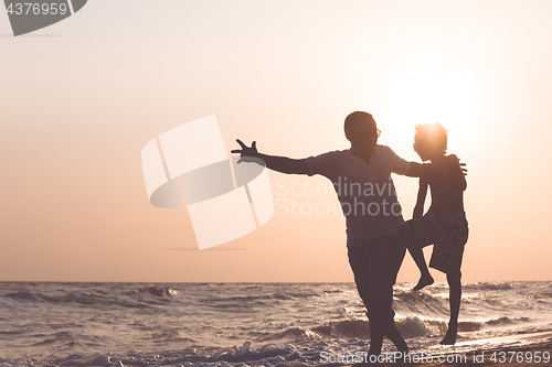 Image of Father and son  playing on the beach at the sunset time.