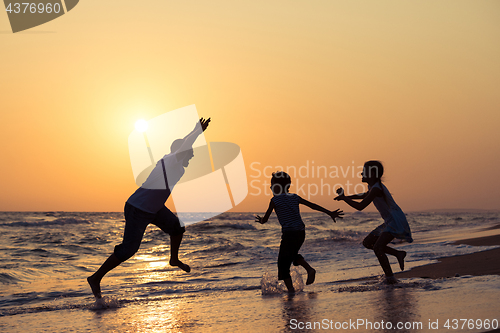 Image of Father son and daughter playing on the beach at the sunset time.