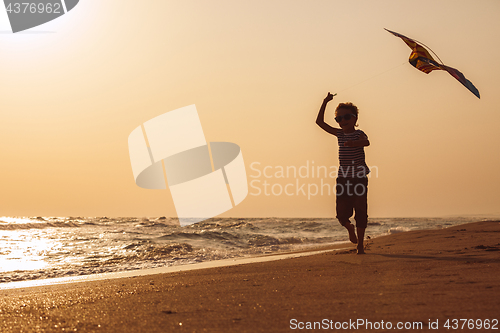 Image of One happy little boy playing on the beach at the sunset time.