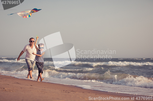 Image of Father and son playing on the beach at the day time.