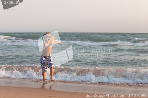 Image of One happy little boy playing on the beach at the day time.