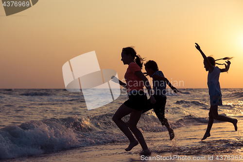 Image of Happy children playing on the beach at the sunset time.