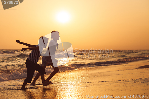 Image of Happy children playing on the beach at the sunset time.