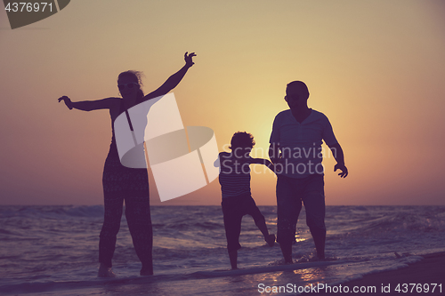 Image of Father mother and  son  playing on the beach at the sunset time.