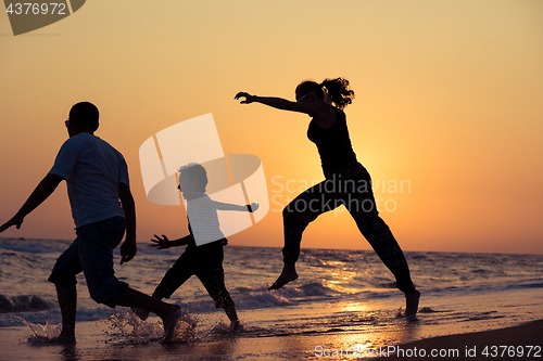 Image of Father mother and  son  playing on the beach at the sunset time.