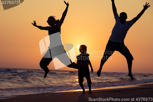 Image of Father mother and  son  playing on the beach at the sunset time.