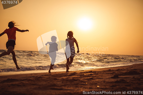 Image of Happy children playing on the beach at the sunset time.