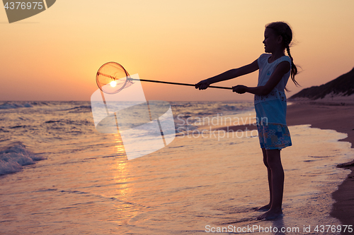 Image of One happy little girl playing on the beach at the sunset time.