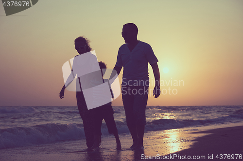 Image of Father mother and  son  playing on the beach at the sunset time.