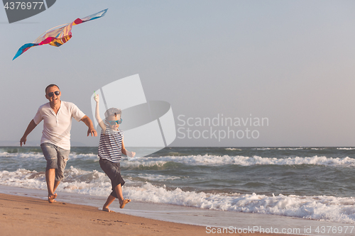 Image of Father and son playing on the beach at the day time.