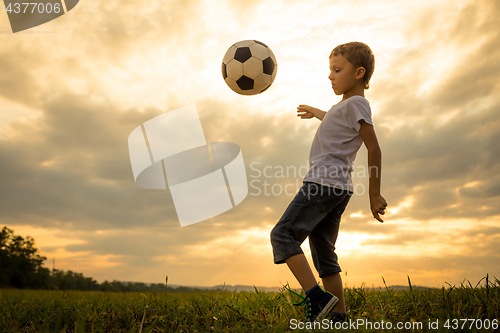 Image of Young little boy playing in the field  with soccer ball.