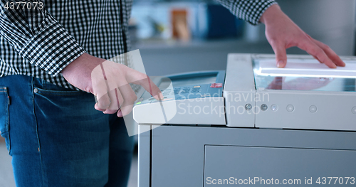 Image of Male Assistant Using Copy Machine in modern office