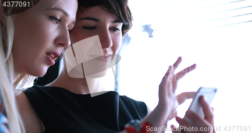 Image of two attractive business women with a cell phone discuss business