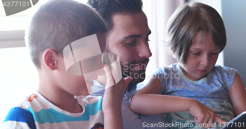 Image of father and two kids having fun together at home