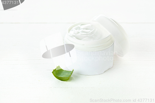 Image of Opened plastic container with cream and aloe on a white background.