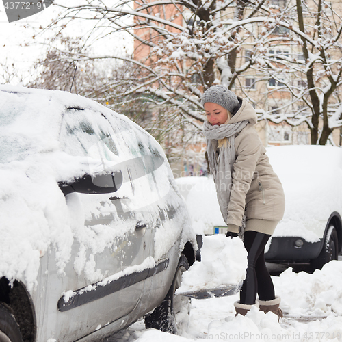 Image of Independent woman shoveling snow in winter.