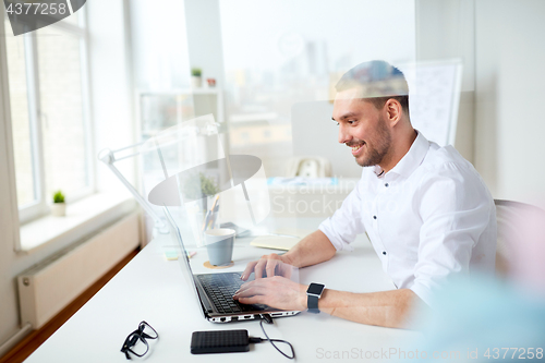 Image of happy businessman typing on laptop at office