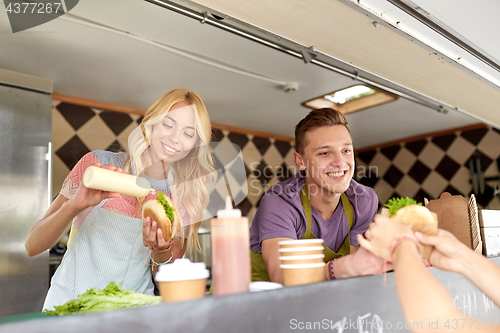 Image of happy sellers serving customers at food truck