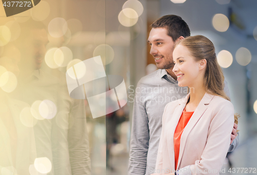 Image of happy couple looking to shop window in mall