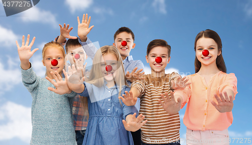 Image of happy children waving hands at red nose day