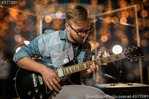 Image of musician playing guitar at studio over lights