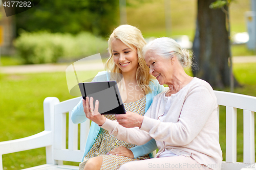 Image of daughter and senior mother with tablet pc at park