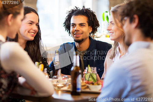 Image of happy friends eating at bar or restaurant