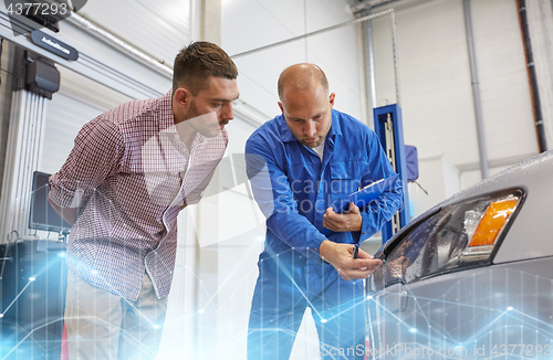 Image of auto mechanic with clipboard and man at car shop