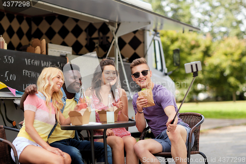 Image of happy young friends taking selfie at food truck