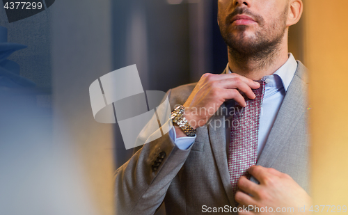 Image of close up of man trying tie on at mirror