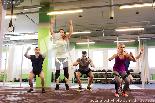 Image of group of people exercising and jumping in gym