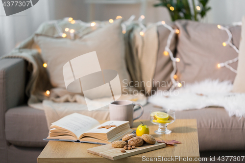 Image of oat cookies, book, tea and lemon on table at home