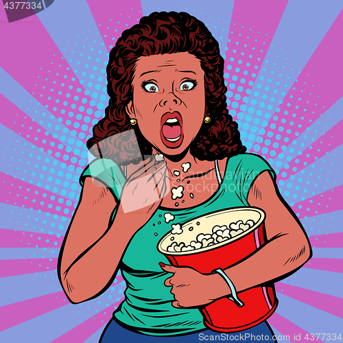 Image of Woman watching a scary movie and eating popcorn