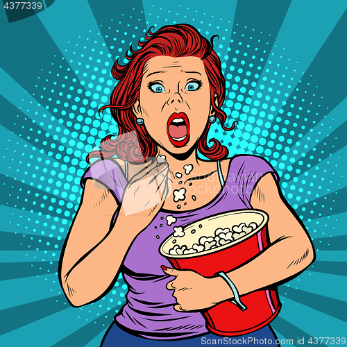 Image of Woman watching a scary movie and eating popcorn