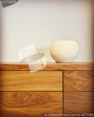 Image of White ceramic vase on a wooden chest of drawers