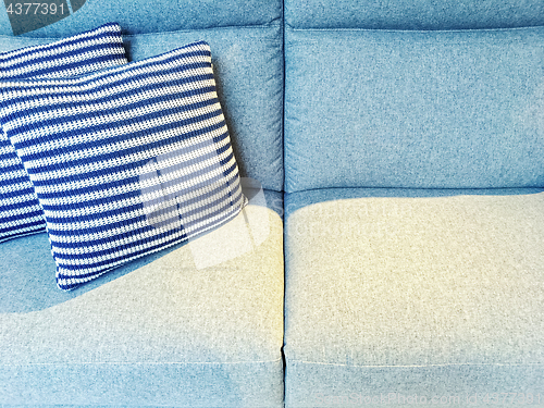 Image of Striped cushions on a blue textile sofa