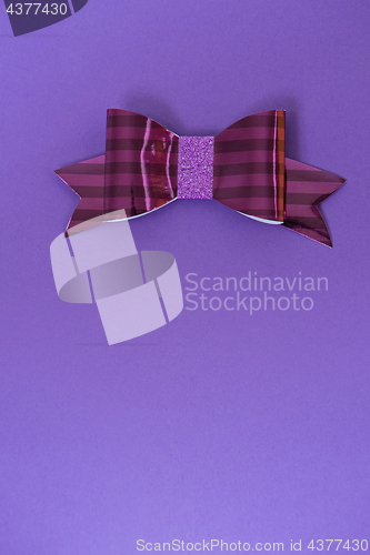 Image of Pink and red striped bow tie over ultra violet background.