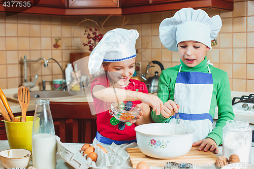 Image of happy family funny kids are preparing the dough, bake cookies in the kitchen