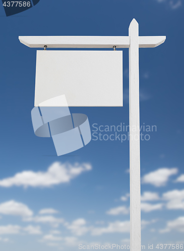 Image of Blank Real Estate Sign Over A Blue Sky with Clouds.