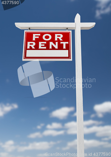 Image of Left Facing For Rent Real Estate Sign on a Blue Sky with Clouds.