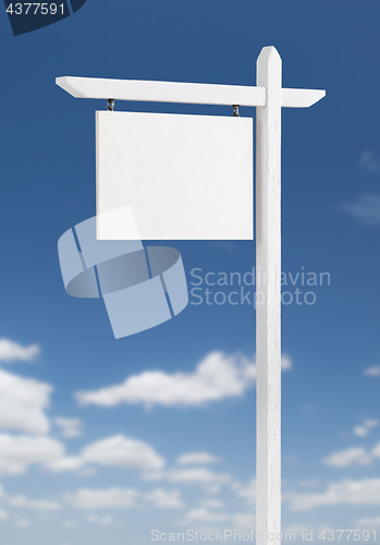 Image of Blank Real Estate Sign Over A Blue Sky with Clouds.