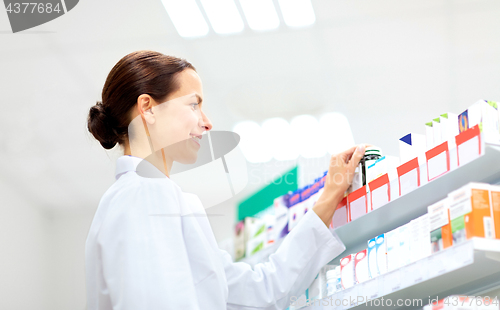 Image of happy female apothecary with drug at pharmacy