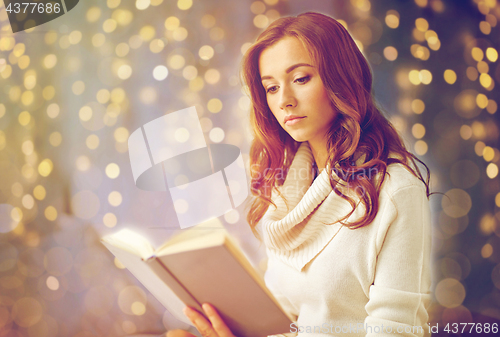 Image of young woman reading book at home