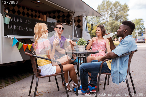 Image of friends with drinks sitting at table at food truck