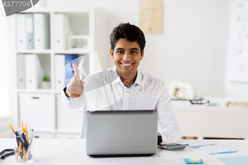 Image of businessman showing thumbs up at office